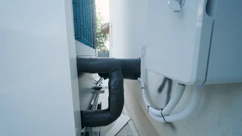 Modern outdoor air-source heat pump unit with a large fan on a white residential Stock Footage 340112941