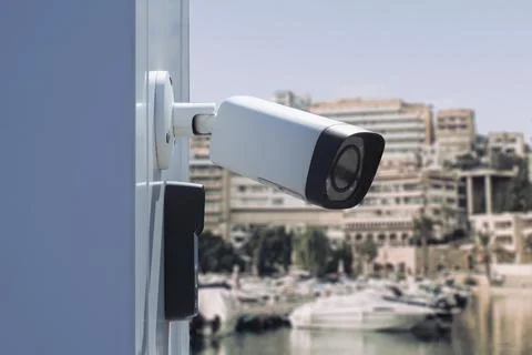 Modern outdoor CCTV security camera on building wall monitoring waterfront ma Stock Photos