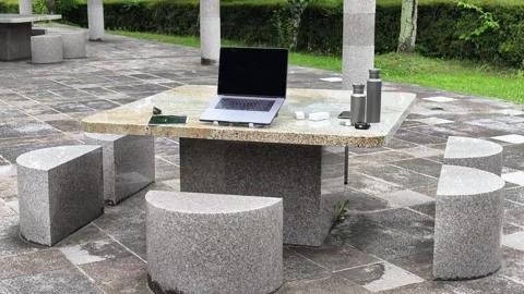 Modern outdoor stone table with laptop and cups Stock Footage 340433100
