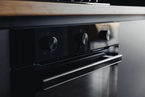 Modern oven with sleek black knobs and reflective door Foto stock