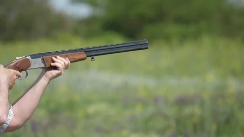 Modern over and under rifle targeting clay pigeons on a big range in slow motion Stock Footage