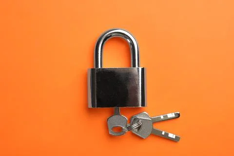 Modern padlock with keys on orange background, top view Stock Photos