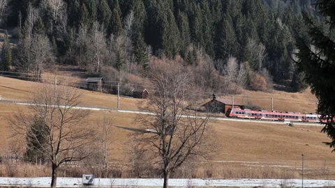 Modern passenger train moving across alpine countryside Stock Footage 331257363
