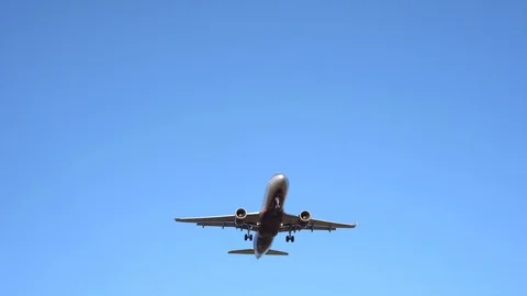Modern plane flies overhead, with a cloudless blue sky in the background. 4K Stock Footage 117376672