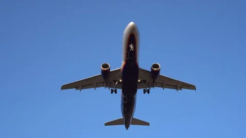 Modern plane flies overhead, with a cloudless blue sky in the background. 4K Stock Footage 117376732