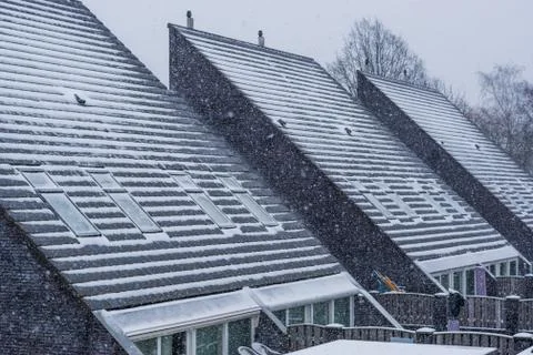 Modern pointed rooftops covered in snow, snowy and cold weather in winter sea Stock Photos