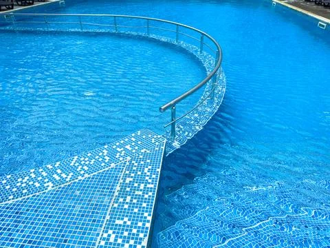 Modern pool design with curved edge and clear blue water in a resort settin.. Fotos de archivo