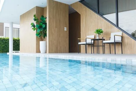 Modern poolside seating area with plants and wooden accents Stock Photos