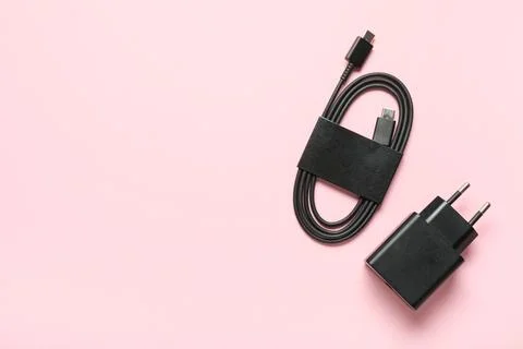 Modern power adapter and type-c cable on pink background, top view Stock Photos