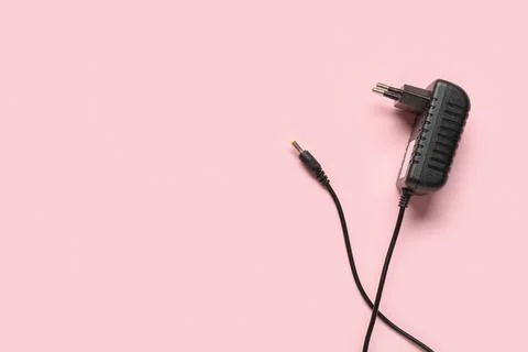 Modern power adapter with cable on pink background, top view Stock Photos