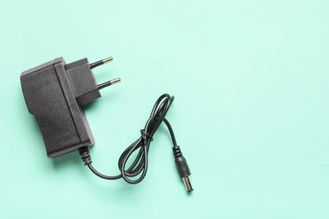 Modern power adapter with cable on turquoise background, top view Stock Photos