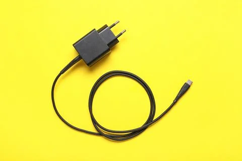 Modern power adapter with type-c cable on yellow background, top view Stock Photos