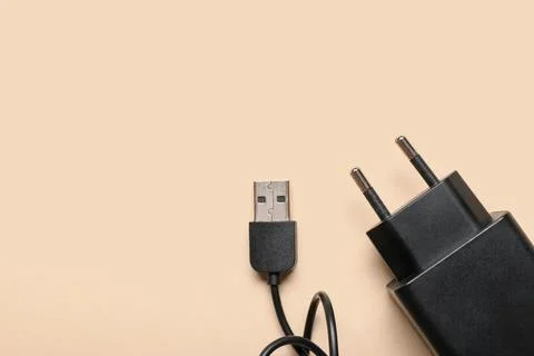 Modern power adapter with USB cable on beige background, top view Stock Photos
