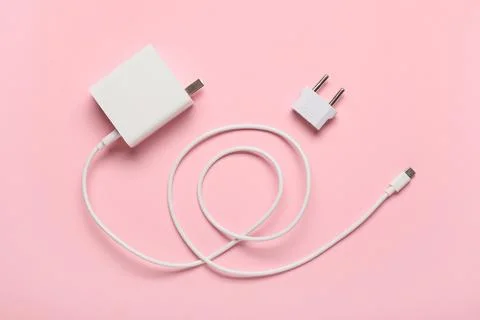 Modern power adapter, USB cable and plug head on pink background, top view Stock Photos