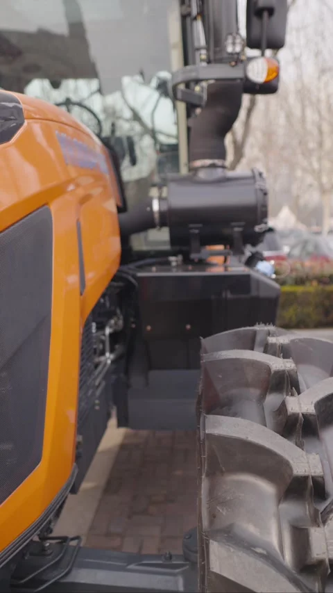 Modern powerful orange tractor with large wheels displayed at outdoor Stock Footage 328987880