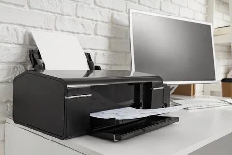 Modern printer with computer on desk in office Stock Photos