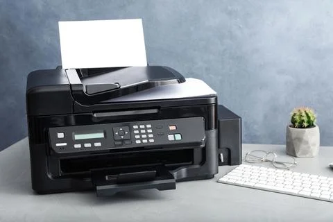 Modern printer with paper and computer keyboard on grey table Stock Photos