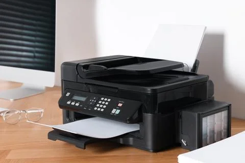 Modern printer with paper near computer on wooden table in office 스톡 사진