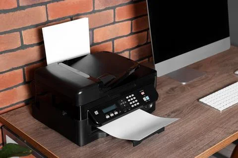 Modern printer with paper near computer on wooden desk at home Stock Photos
