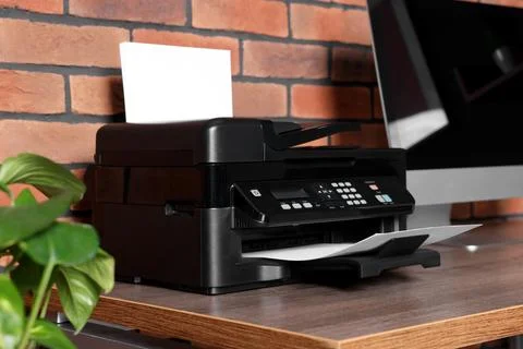 Modern printer with paper near computer on wooden desk at home Stock Photos