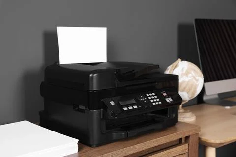 Modern printer with paper near computer on wooden desk at home Stock Photos