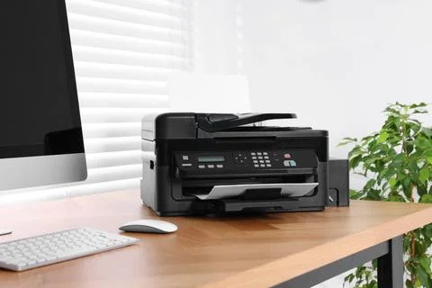 Modern printer with paper near computer on wooden table in home office Stock Photos
