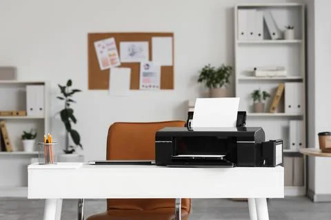 Modern printer with paper sheets and laptop on desk in office Stock Photos
