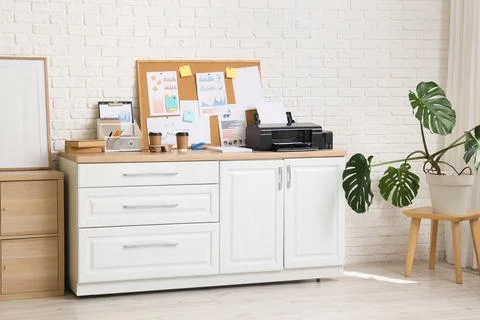 Modern printer with paper sheets and pin board on shelf in office interior Stock Photos