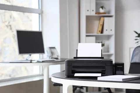 Modern printer with paper sheets on desk in office Stock Photos