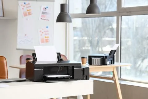 Modern printer with paper sheets on desk in office Stock Photos