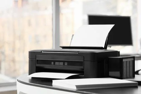 Modern printer with paper sheets on desk in office Stock Photos