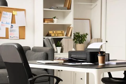 Modern printer with paper sheets on table in office interior Stock Photos