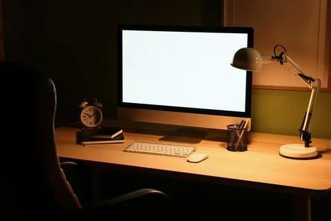 Modern programmer's workplace with computer monitor, alarm clock and glowing  Stock-Fotos