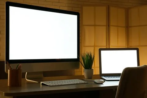 Modern programmer's workplace with computer monitor, laptop and houseplant in Stock-Fotos