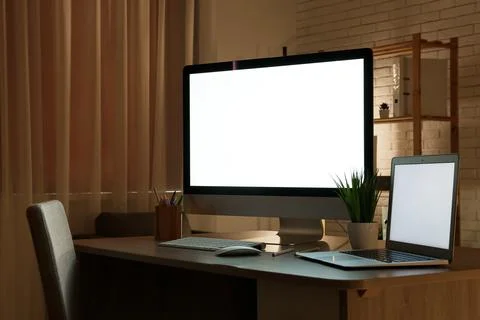 Modern programmer's workplace with computer monitor, laptop and houseplant in Stock-Fotos
