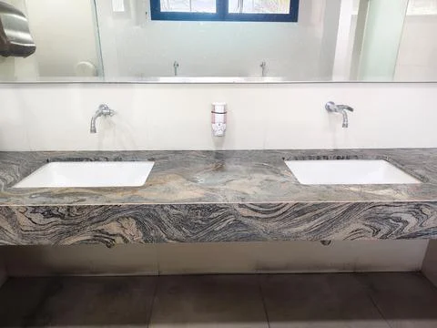 Modern public restroom interior featuring two white sinks Stock Photos
