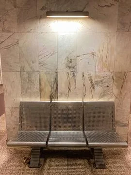 A modern public seating area featuring a perforated metal bench and marbled b Stock Photos