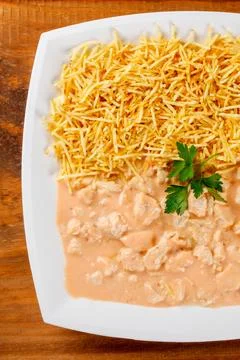 A modern rectangular plate with chicken stroganoff in a pink sauce and 库存照片