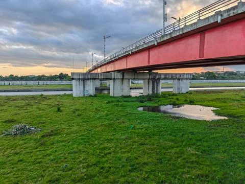Modern red bridge structure over a calm river Stock Photos