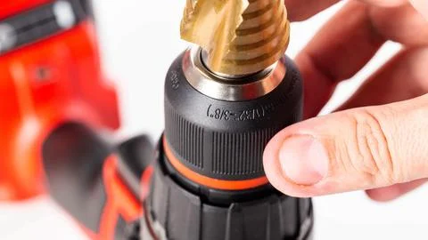 Modern red drill screwdriver with step drill bit in keyless chuck on white Photos