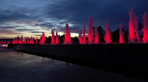 Modern red lit park fountains against late sunset sky. Architectural LED Stock Footage