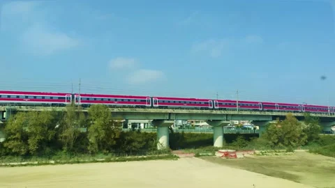 A Modern Red Train on a Bridge Against a Blue Sky on a Warm Summer Day in Italy Stock Footage 231574935