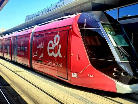 A modern, red tram with "e&amp;" and "RTA" logos on its side Stock Photos