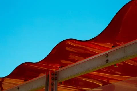 Modern Red, Wavy Patterned Rooftop with Blue Sky Stockfoto's