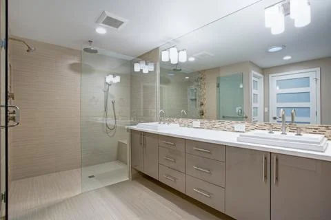 Modern refreshing bathroom features a beige dual washstand accented with mosa Stock Photos