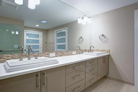 Modern refreshing bathroom features a beige dual washstand accented with mosa Stock Photos