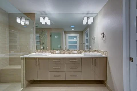 Modern refreshing bathroom features a beige dual washstand accented with mosa Stock Photos