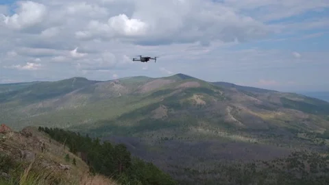 Modern remote controlled quadcopter drone flying over scenic mountain landscape. Stock Footage 319812737