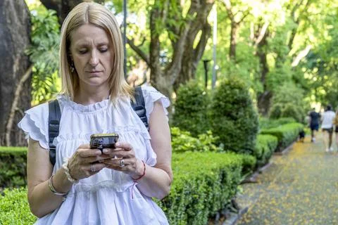 Modern remote worker or freelancer using a cell phone app while standing in.. Stock Photos
