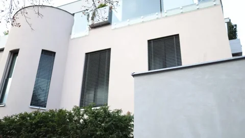 Modern residential building with light-colored facade, vertical windows, and clo Stock Footage 304885414
